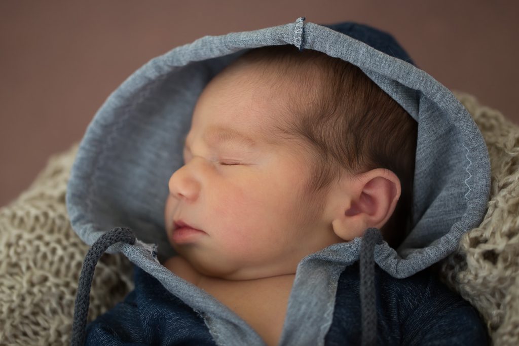 Neugeborenes liegt in einer Schale und schläft. nahaufnahme vom gesicht. neugeborenenfotos von Ella Photography bei duesseldorf
