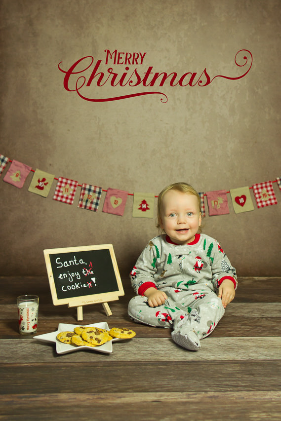 kleiner junge sitzt in einem weihnachtlichen Schlafanzug neben einem teller kekse und wartet auf den weihnachtsmann, fotos für weihnachten von ella photography bei duesseldorf