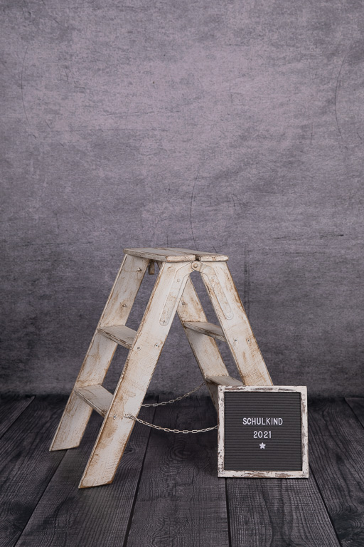 weiße Leiter mit kleiner Tafel davor, vor grauem hintergrund, ella photography erkrath