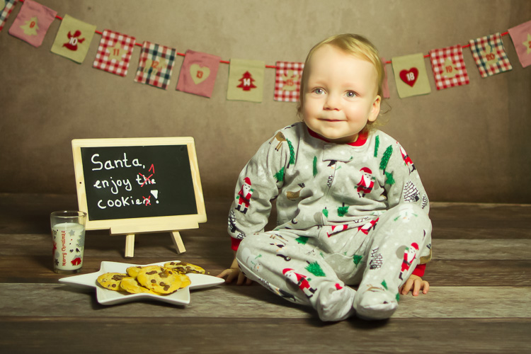 kleiner junge sitzt in einem weihnachtlichen Schlafanzug neben einem teller kekse und wartet auf den weihnachtsmann, fotos für weihnachten von ella faust bei duesseldorf